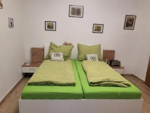 默尔巴赫Appartement Purzel的配有绿床单和枕头的客房内的两张床