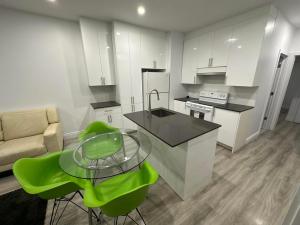 蒙特利尔Appartement 2 chambres - 202的厨房配有玻璃桌和绿色椅子