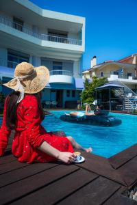 DhráfiReunion in Greece Villa的坐在游泳池旁的戴帽子的女人
