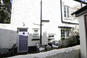 林茅斯Ferndale Cottage的白色的建筑,配有两把椅子和一扇紫色的门