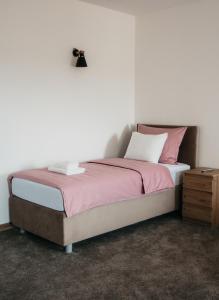 Babina GredaPansion Mihića dvori的一间卧室配有一张带粉色床单的床和床头柜。