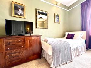 萨彻姆Colthrop Manor B&B的一间卧室配有两张床、一台电视和一个梳妆台。