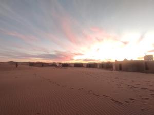 MhamidWüstencamp in Erg Chegaga的沙漠中的日落,有人在沙子里散步