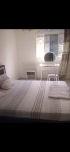 莫罗尼Cosy Home Sweet Home的一间卧室配有一张床、一张桌子和一个窗户。