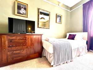 萨彻姆Colthrop Manor with Gardens的一间卧室配有一张床和一个带电视的梳妆台