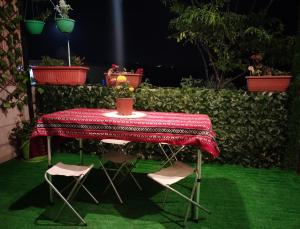 乌姆盖斯Seleucia DaR Umm Qais的一张桌子,两把椅子,一张桌子,一张桌子,一张桌子,上面有红色的桌布