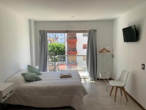布宜诺斯艾利斯Monoambiente nuevo y luminoso en Flores的卧室配有床、椅子和窗户。