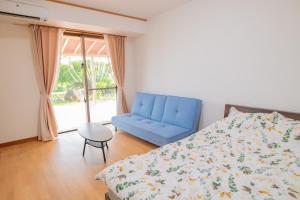 宫古岛さつきあん的一间卧室配有一张床和一张蓝色的沙发
