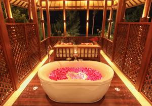 Ketewel阿纳普利别墅的阳台上配有装满粉红色花卉的浴缸