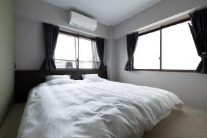 KinosakiHOSTEL Waraku的卧室配有一张白色大床和两个窗户