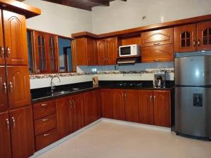 麦德林Casa Nogal 76的厨房配有木制橱柜和不锈钢冰箱。