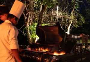 锡吉里亚Lario Resort Sigiriya的站在烧烤架旁的厨师帽上的人