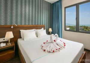 岘港L'emore Hotel Da Nang的一间卧室配有一张带天鹅装饰的床。