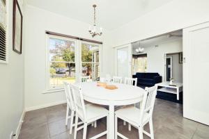 West Richmond6 BR House Near Adelaide Airport的一间设有白色桌子和白色椅子的用餐室