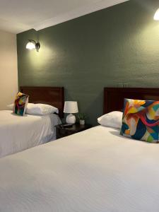 危地马拉Inari Hostal的一间卧室设有两张床和绿色的墙壁