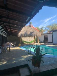 马那瓜hotel Las Cabañitas 8873-3748的一个带茅草伞和房子的游泳池