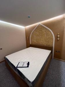 塔什干Hamsa Butique Hotel Tashkent的一张床上的房间,上面有白色的床垫和标志