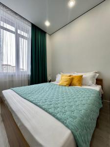 阿斯塔纳1-комнатная возле Посольства США и Мечети Хазрет Султан的一间卧室配有一张带绿色棉被的大床