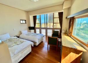 热海Hostel and Cafe izu-no-umi的酒店客房设有两张床、一张书桌和一个窗户。