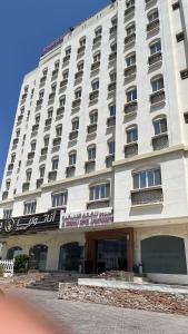 马斯喀特Al Murooj Hotel Apartments的一座白色的大建筑,上面有标志