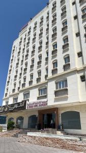 马斯喀特Al Murooj Hotel Apartments的一座白色的大建筑,上面有标志