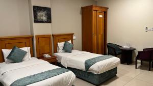 马斯喀特Al Murooj Hotel Apartments的酒店客房,配有两张床和椅子