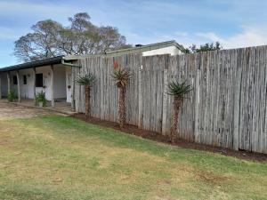 格拉罕镇The Ranch House at African Safari Lodge的房屋前有两棵棕榈树的围栏