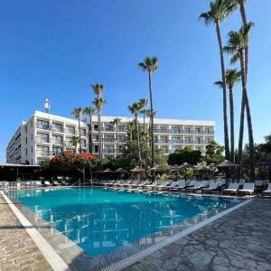 帕福斯维罗尼卡酒店的酒店设有带椅子和棕榈树的游泳池