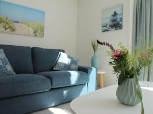 斯霍尔Stunning apartment in Schoorl North Holland you can bike to the beach的客厅配有沙发和带花瓶的桌子