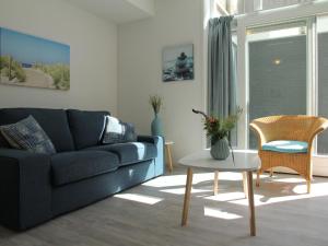 斯霍尔Stunning apartment in Schoorl North Holland you can bike to the beach的客厅配有蓝色的沙发和桌子