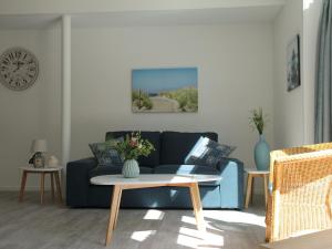 斯霍尔Stunning apartment in Schoorl North Holland you can bike to the beach的客厅配有蓝色的沙发和桌子