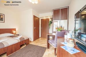 斯维诺乌伊希切Baltic Apartments - Hotelik Przy Promenadzie的酒店客房配有一张床、一张书桌和一台电视。