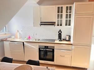 多斯滕Dachgeschoss-Maisonette-Apartment mit Klimaanlage的厨房配有白色橱柜和炉灶烤箱。