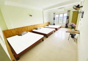 广宁Coto Plus Hotel & Restaurant的鲜花盛开的房间里一排床