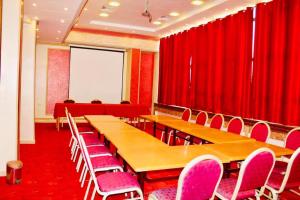 奥兰Hotel Les Ambassadeurs的一间会议室,配有红色窗帘和木桌及椅子