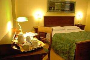 巴勒莫戴尔中央酒店的一间酒店客房,配有一张床铺和一张桌子,并提供盘子