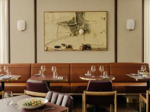 波兹南PURO Hotel Poznań Stare Miasto的餐厅设有桌椅,墙上挂有绘画作品