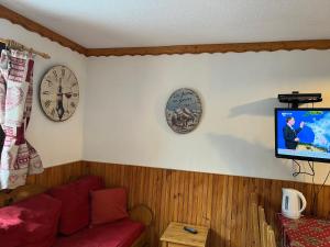 里蒙纽耶La Villaret的客厅配有沙发和墙上的两把钟