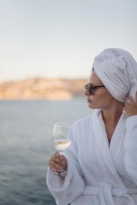 阿齐亚佩拉加半岛Spa度假村的一位拿着一杯白葡萄酒的女人