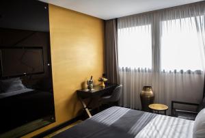 特拉维夫Brown Lighthouse Tel Aviv, a member of Brown Hotels的配有一张床、一张书桌和一扇窗户的酒店客房