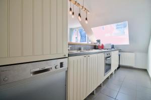 布鲁塞尔Heart of Grand Place - Stunning 2BR Duplex的厨房配有白色橱柜和不锈钢用具