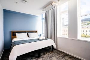 惠灵顿Haka House Wellington的一间卧室配有一张蓝色墙壁的床和一扇窗户
