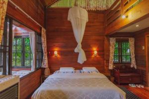 清迈Muangkham Cabin的卧室配有一张床铺,位于带木墙的房间内