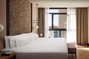 塞维利亚塞维利亚NH酒店集团的卧室设有一张白色大床和一扇窗户。