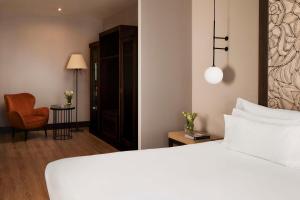 塞维利亚塞维利亚NH酒店集团的卧室配有白色的床和椅子