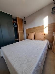 博尼法乔Chalet n * 1 au cœur du maquis的卧室配有一张带白色床单和枕头的大床。