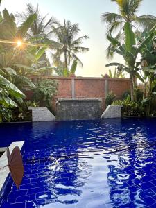 暹粒Angkor Sand Hotel的一座拥有蓝色海水和棕榈树的游泳池