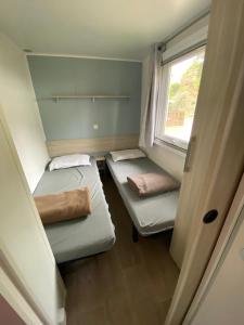 纳博讷普拉日Mobil home - Clim, TV - Camping Falaise Narbonne Plage 4 étoiles - 010的小房间设有两张床和窗户