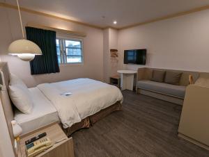 台南康桥商旅 - 台南民生馆 的酒店客房,配有床和沙发