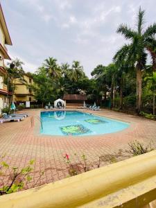 巴加Holidays Beach Apartments Goa的棕榈树庭院内的大型游泳池
